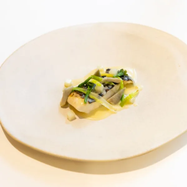 Llom de llobarro amb el seu pil pil, carxofes, porros escalivats i fulles tendres de col